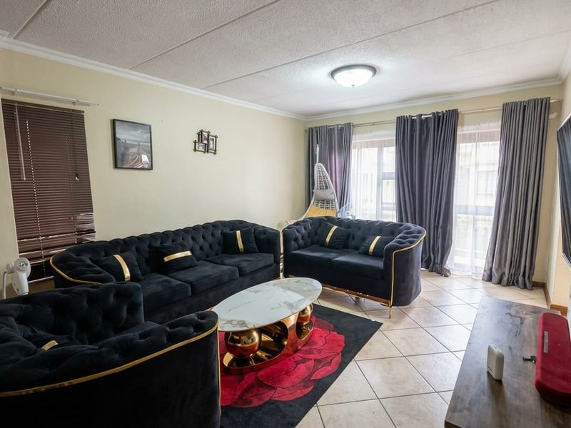 A spacious living room featuring tiled flooring, coved ceilings, and a sliding glass door providing access to the exterior.
