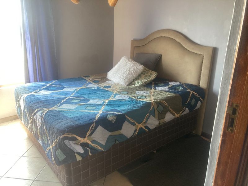 A bedroom featuring tiled flooring and neutral wall finishes, providing a functional space for rest.