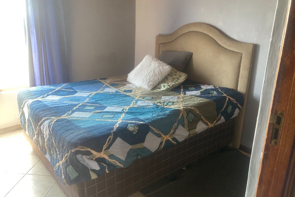 A bedroom featuring tiled flooring and neutral wall finishes, providing a functional space for rest.