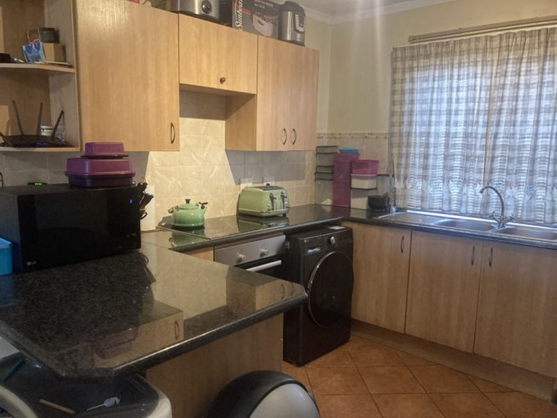 A functional kitchen featuring laminate cabinetry, granite countertops, a built-in oven, and tiled flooring, offering a practical layout for daily meal preparation.