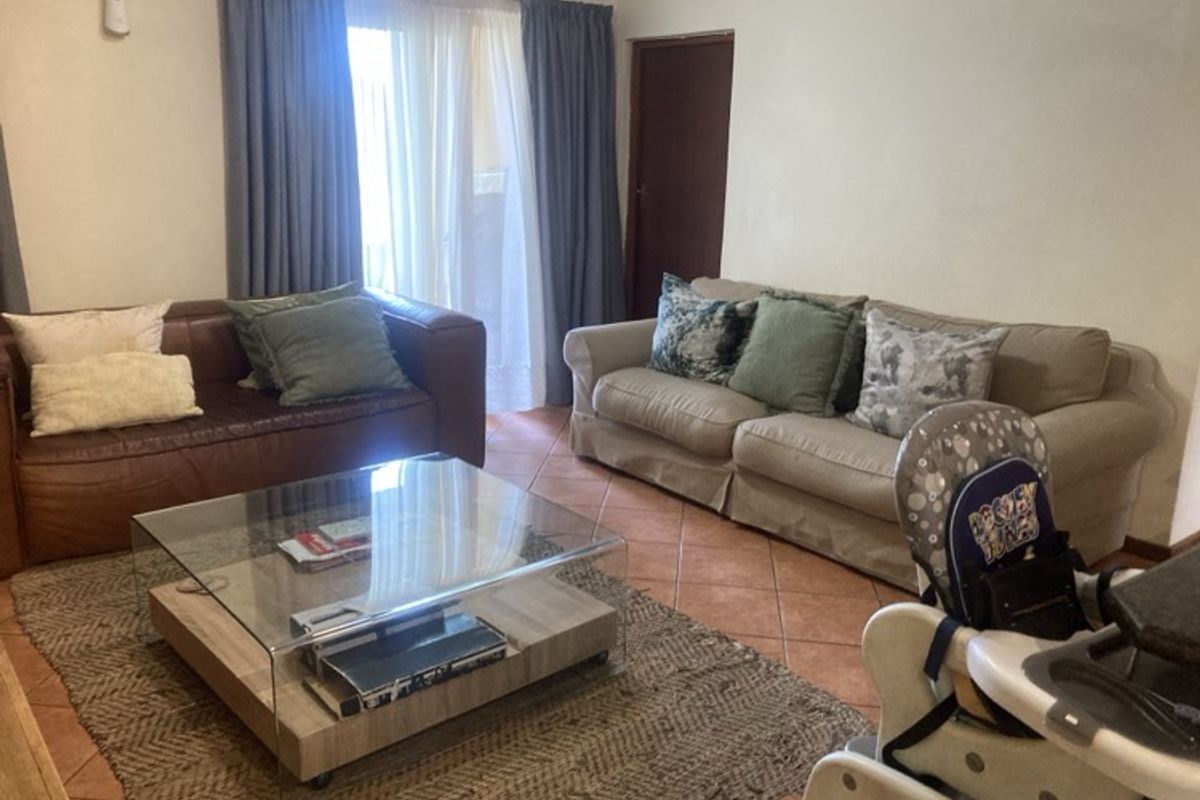 A living room featuring tiled flooring and a sliding glass door providing access to the exterior.