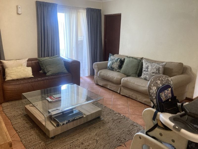 A living room featuring tiled flooring and a sliding glass door providing access to the exterior.
