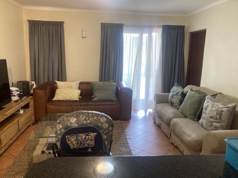 A comfortable living room featuring tiled flooring and a sliding glass door that provides access to the outdoors.