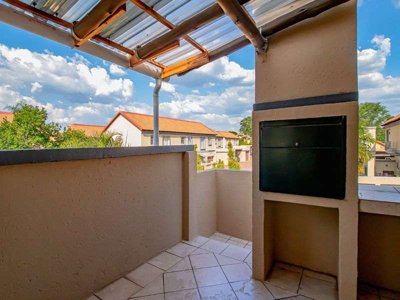 A covered balcony featuring a built-in braai, tiled flooring, and a corrugated roof, offering an outdoor space suitable for entertaining.