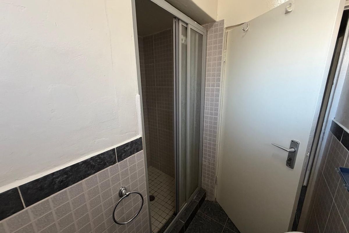 A compact bathroom featuring a shower enclosure with sliding doors, tiled flooring, and wall tiling, presenting an opportunity for modernization.