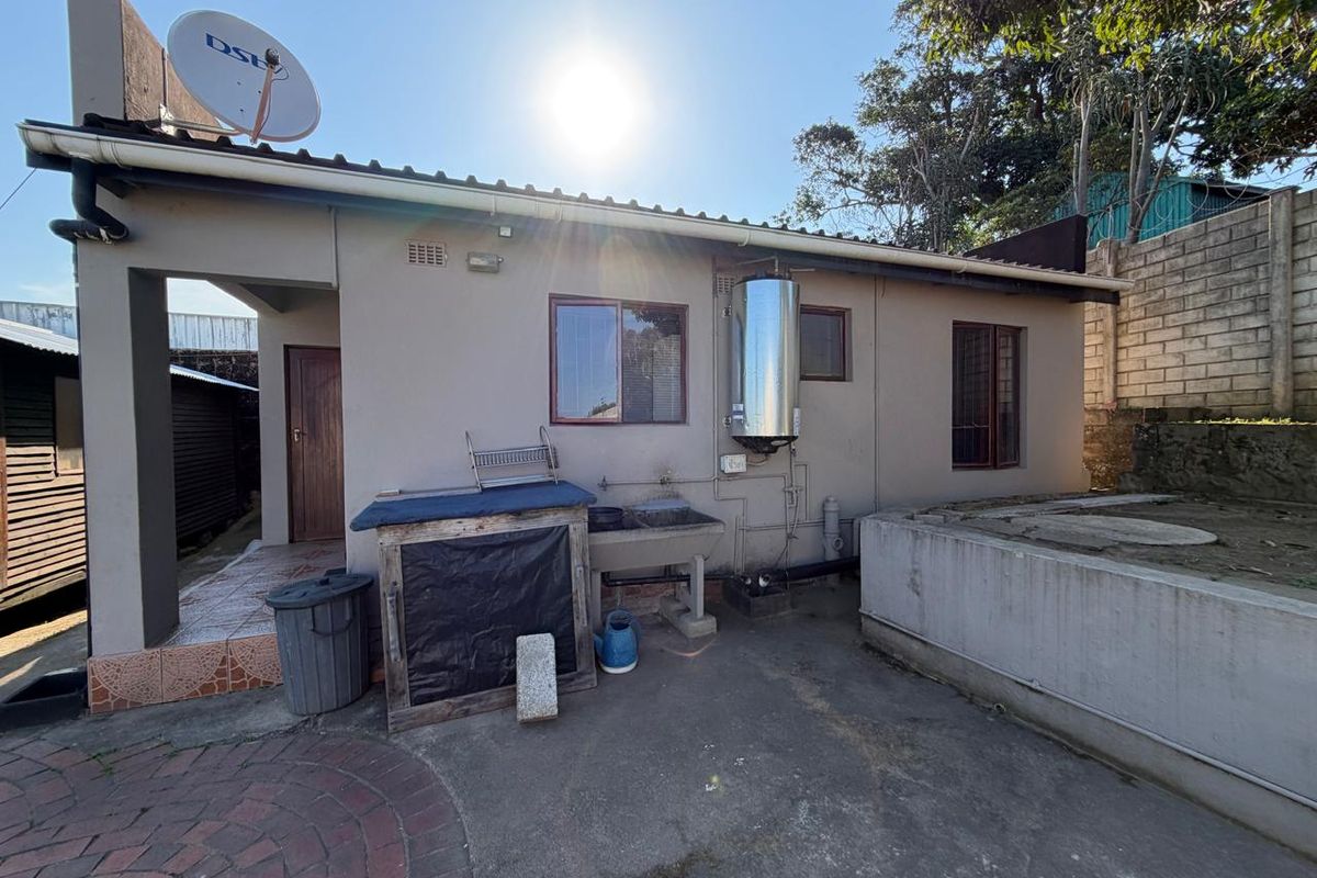 Rear exterior view of the townhouse featuring a paved patio area, external laundry sink, and wall-mounted electric geyser.