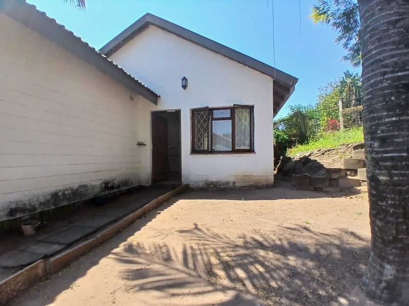 Rear exterior view of the cottage featuring a tiled roof, leaded glass window, and a concrete pathway leading to the entrance.