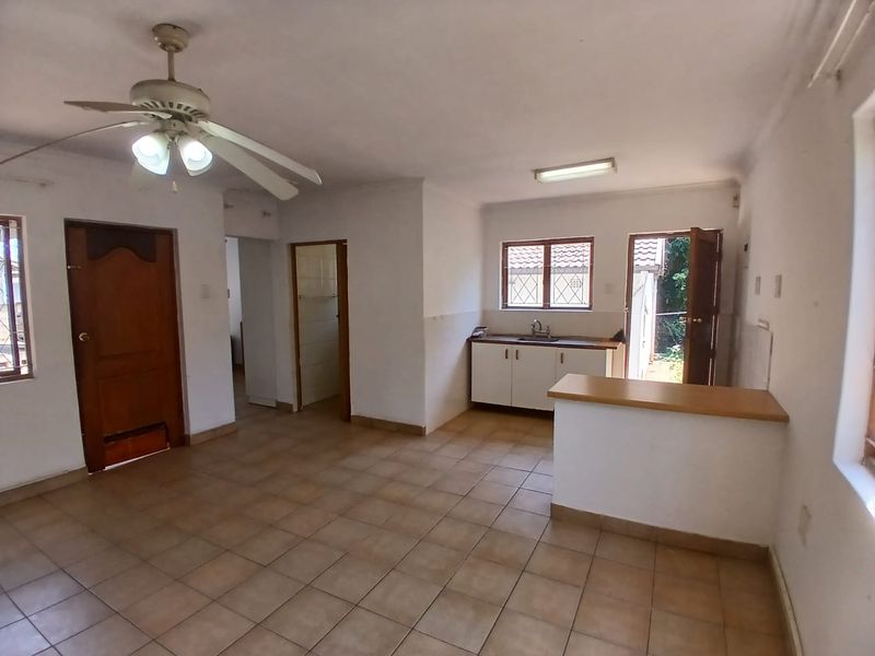 Open plan living and kitchen area featuring tiled flooring, a breakfast bar, and direct access to the exterior.