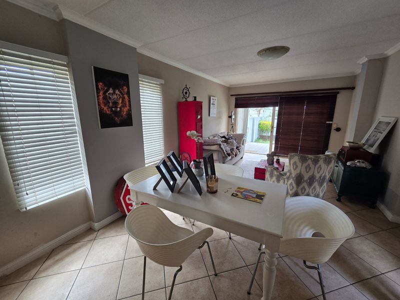 Open plan living and dining area featuring tiled flooring, neutral wall tones, and sliding door access to the outdoor patio space.
