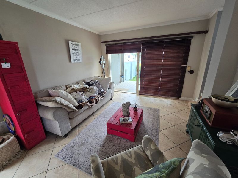 A living room featuring tiled flooring and a sliding glass door that opens to an outdoor patio area.