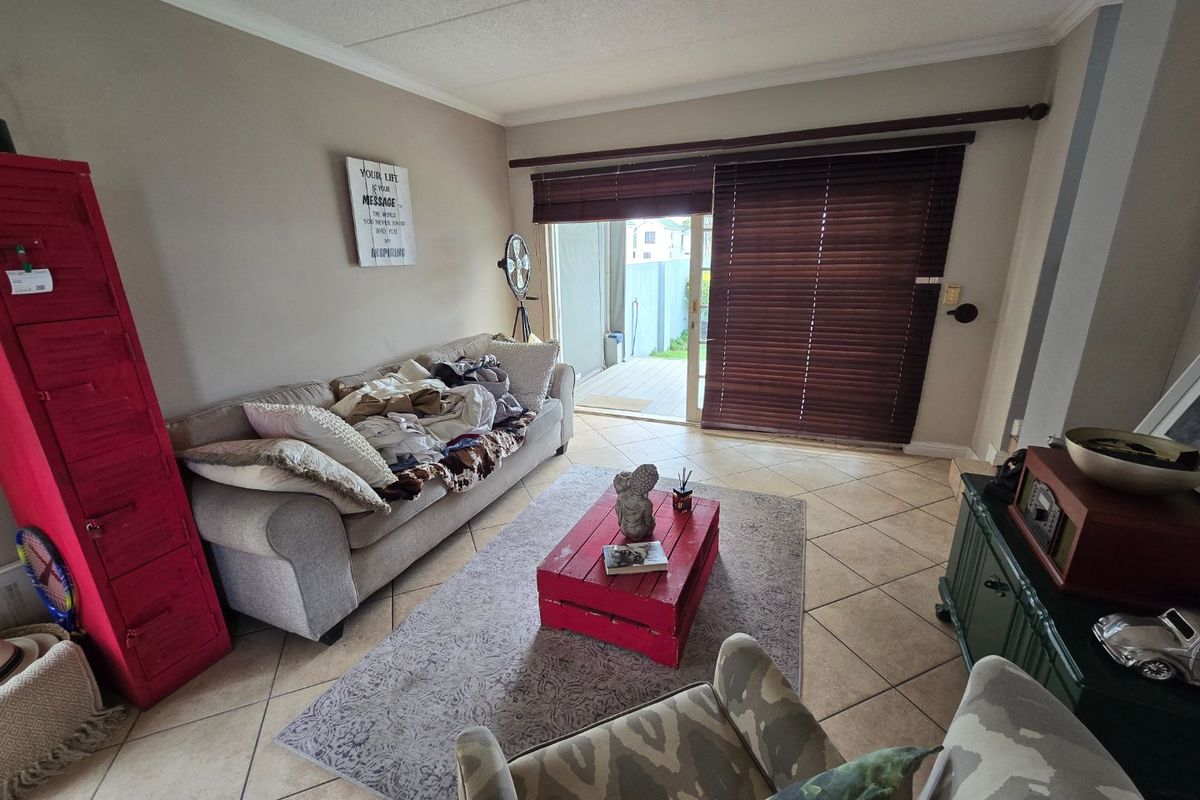 A living room featuring tiled flooring and a sliding glass door that opens to an outdoor patio area.