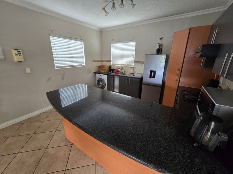 Kitchen featuring granite countertops, built-in cabinetry, tiled flooring, and integrated appliances, offering a functional layout with potential for cosmetic updates.