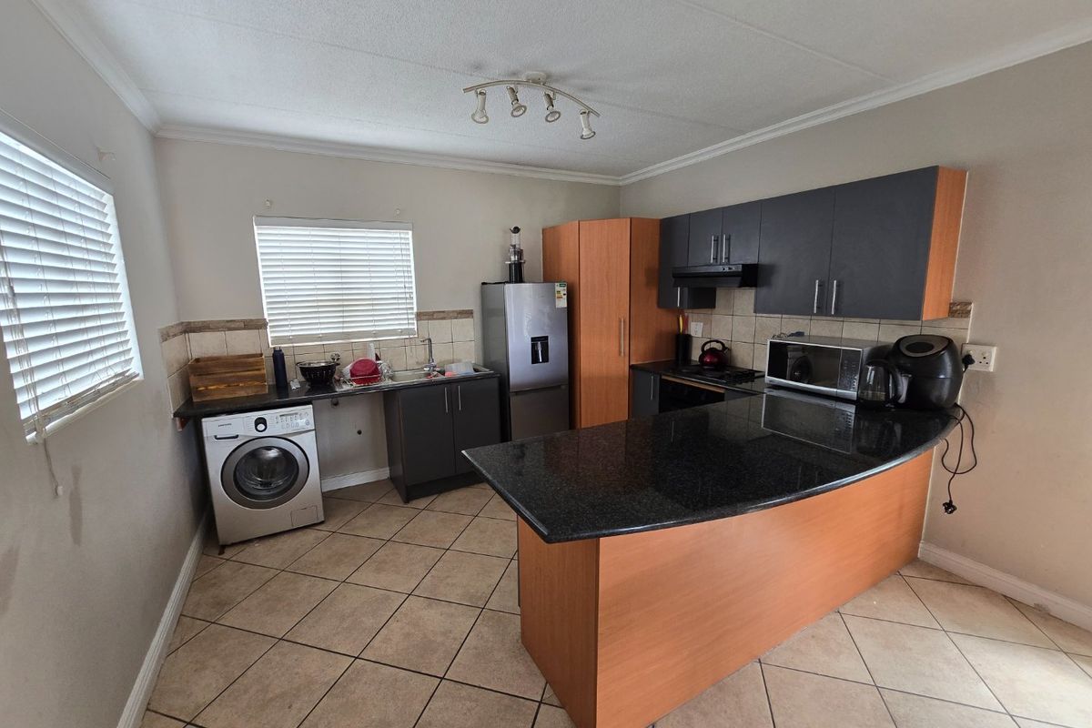 Functional kitchen featuring granite countertops, a central island, built-in cabinetry, and tiled flooring, providing a practical layout for daily meal preparation.