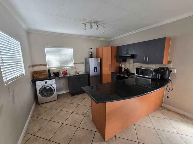 Functional kitchen featuring granite countertops, a central island, built-in cabinetry, and tiled flooring, providing a practical layout for daily meal preparation.