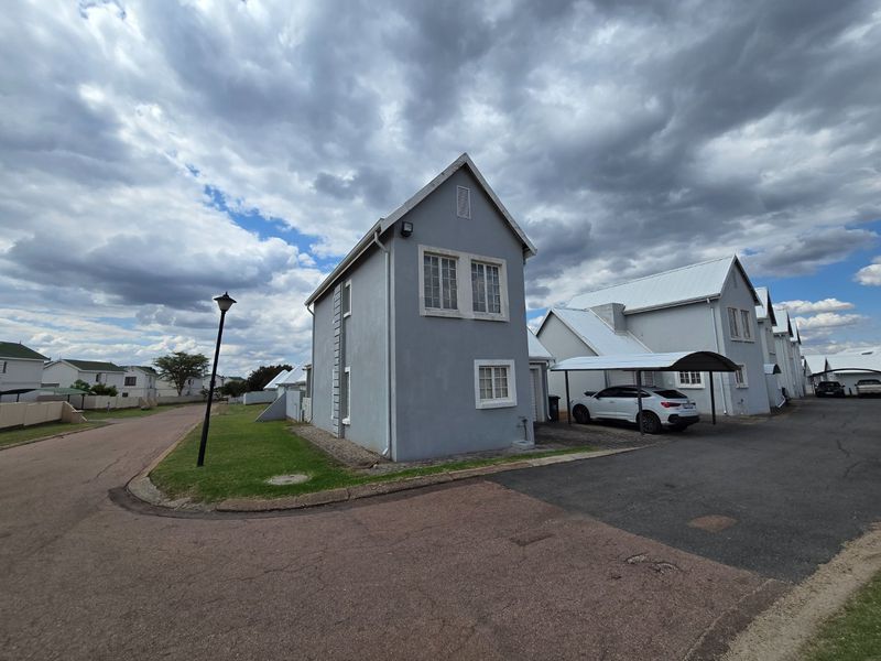 A view of the front elevation of a two-story residential house featuring a paved driveway and a covered carport.