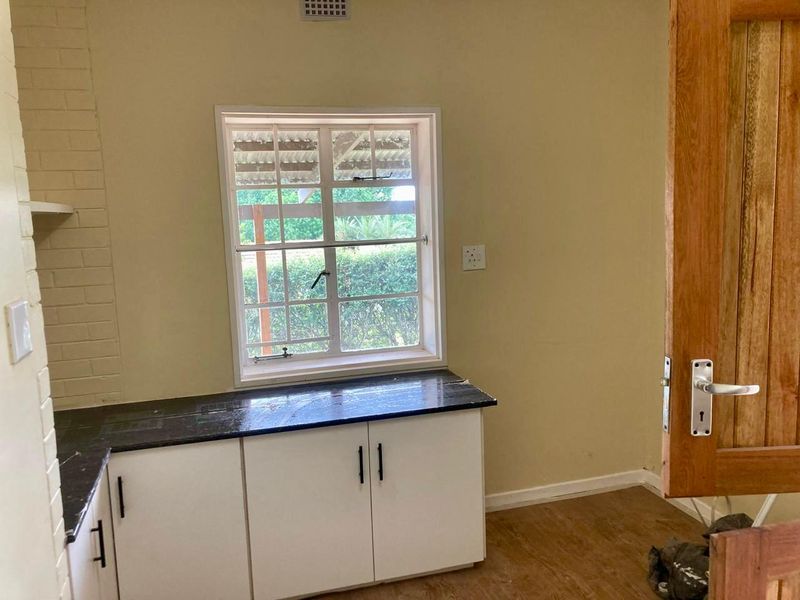 A functional scullery or utility area featuring built-in cabinetry, stone countertops, and a timber door, offering a practical space for food preparation or laundry.