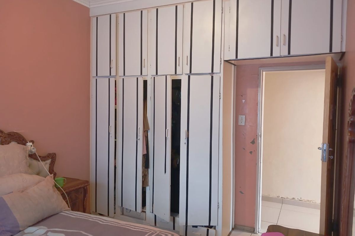 Bedroom featuring built-in cupboards with overhead storage and crown molding. The room requires cosmetic updates including paint and cupboard repairs.