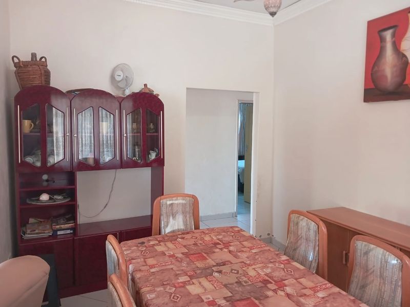 A dining room featuring tiled flooring and decorative coving, with a doorway leading to an adjacent room.