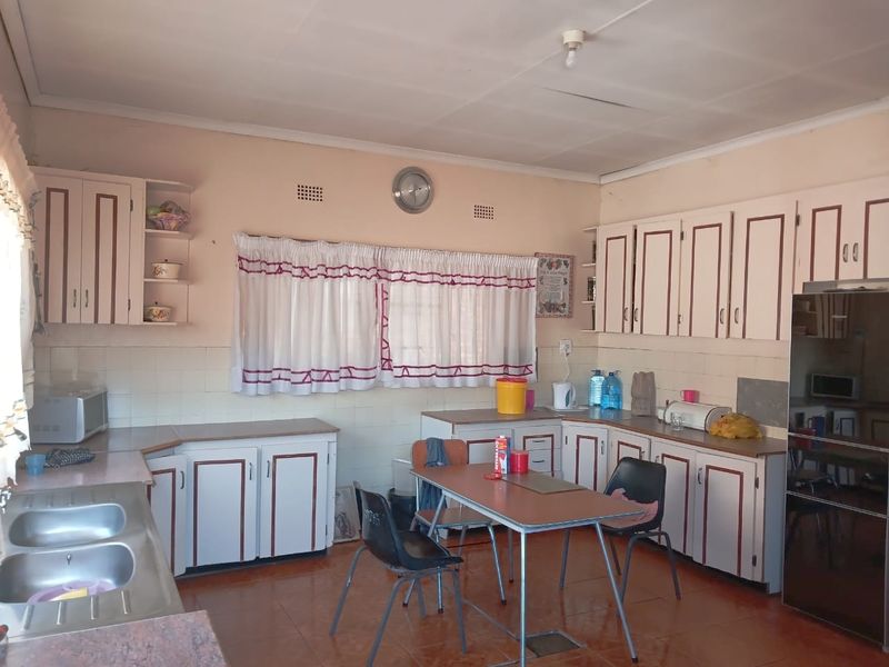 A dated kitchen featuring original built-in cabinetry, a double bowl stainless steel sink, and tiled finishes, offering significant potential for a modern renovation.