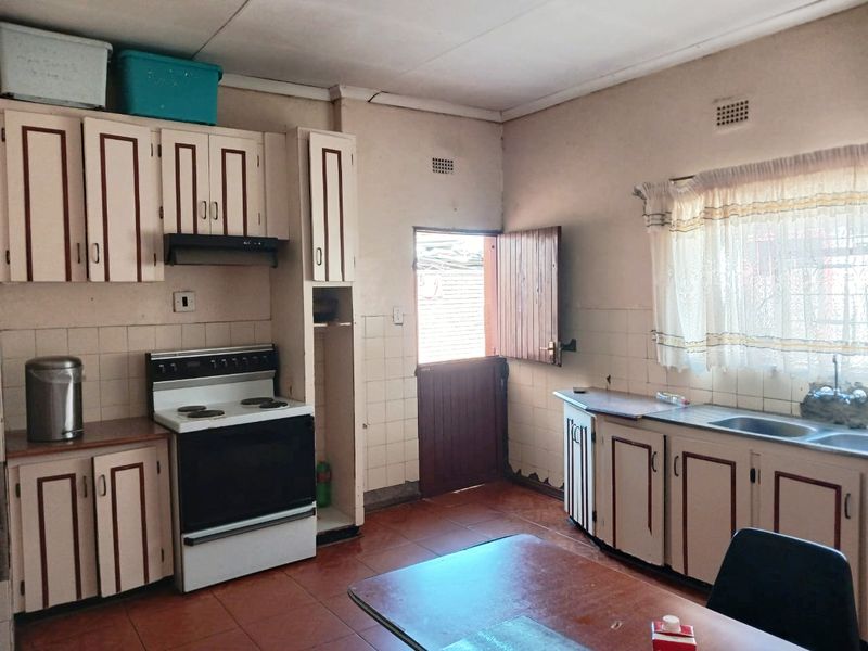 A functional kitchen featuring built-in cabinetry, a tiled backsplash, a freestanding stove with extractor, and a stable door leading to the exterior.