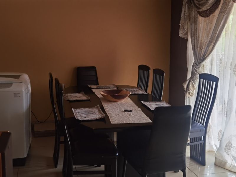 A dining area featuring tiled flooring and a large sliding glass door providing access to the exterior.