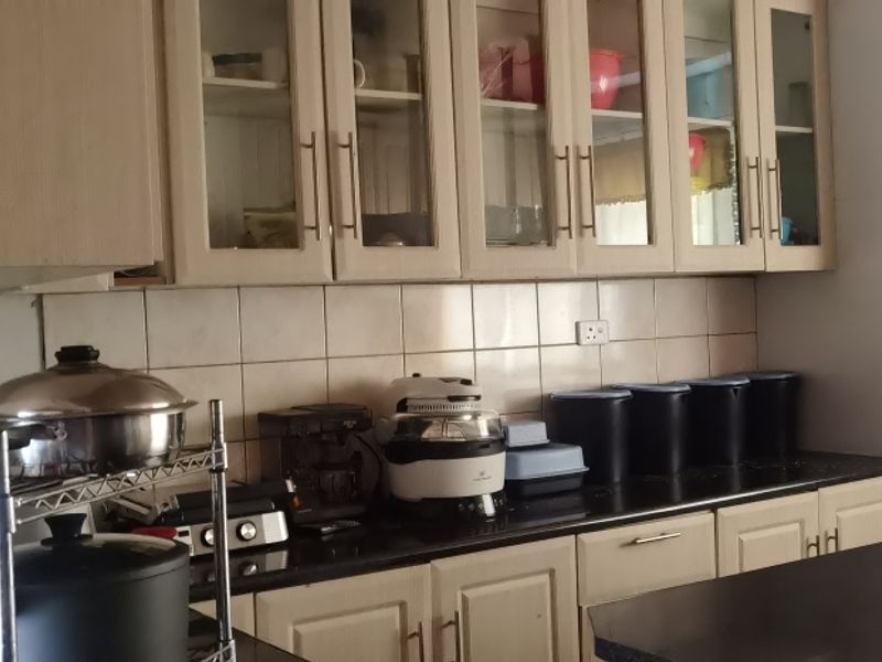 A functional kitchen featuring ample built-in cabinetry with glass-fronted uppers, a tiled backsplash, and dark granite countertops.