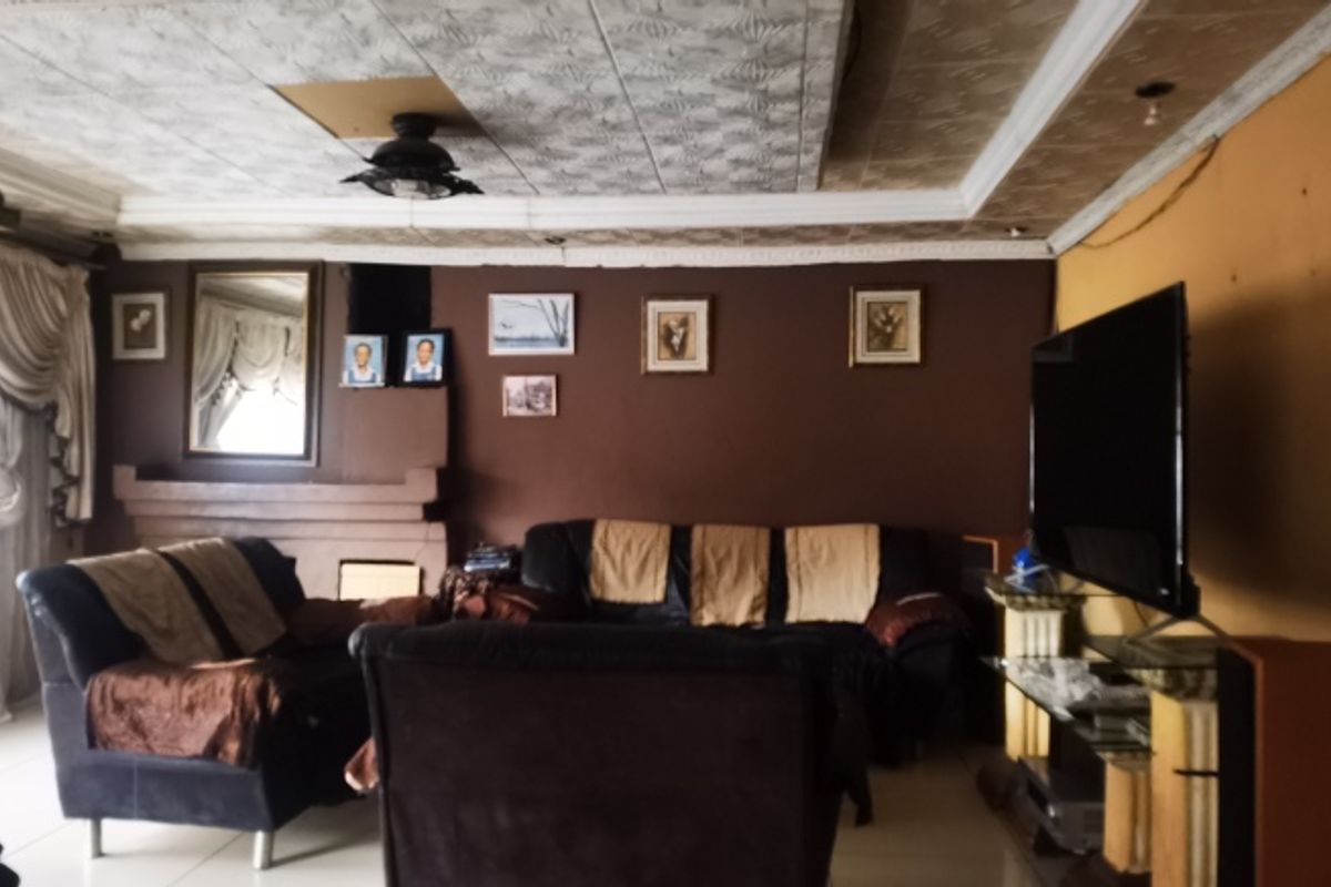 A living room featuring a fireplace, crown molding, and textured ceiling tiles, currently showing signs of wear and requiring cosmetic updates.