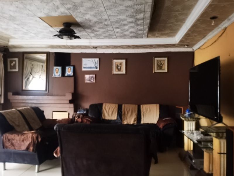 A living room featuring a fireplace, crown molding, and textured ceiling tiles, currently showing signs of wear and requiring cosmetic updates.