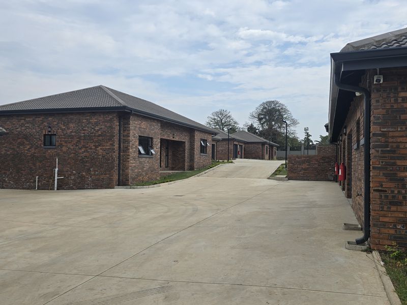A view of the townhouse complex exterior featuring face brick construction, concrete driveway, and multiple garage access points.