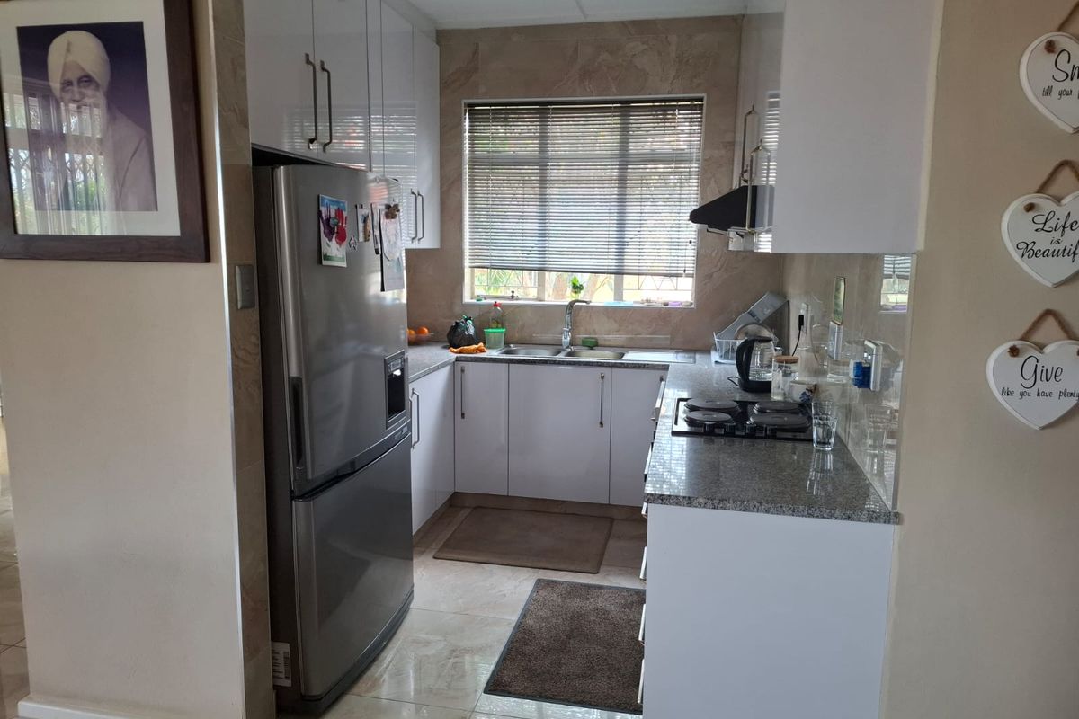 A compact, functional kitchen featuring white cabinetry, granite countertops, a gas hob, and tiled finishes throughout.