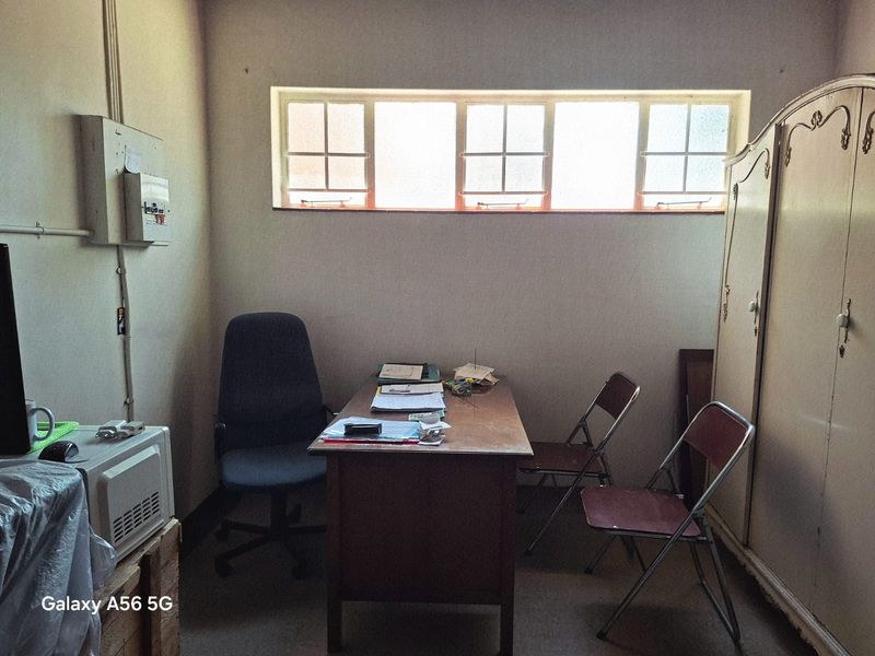 A functional office space featuring a high-level window and exposed electrical infrastructure, suitable for a home workspace or study area.
