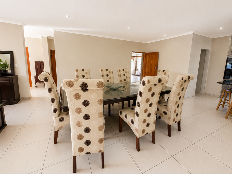 A bright and spacious dining area featuring neutral tiled flooring, recessed downlighting, and a clean, modern aesthetic with open flow to adjacent living spaces.