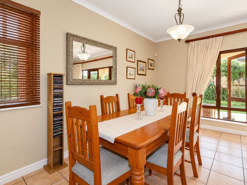 A dining room featuring tiled flooring, timber window and door frames, and direct access to the garden area.