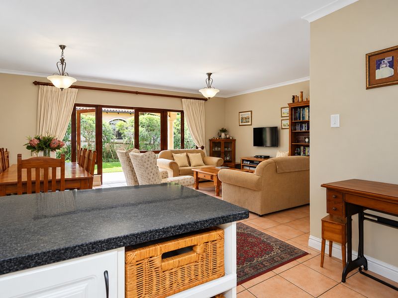 Spacious open-plan living and dining area featuring tiled floors, granite kitchen countertops, and large sliding doors providing direct access to the garden.
