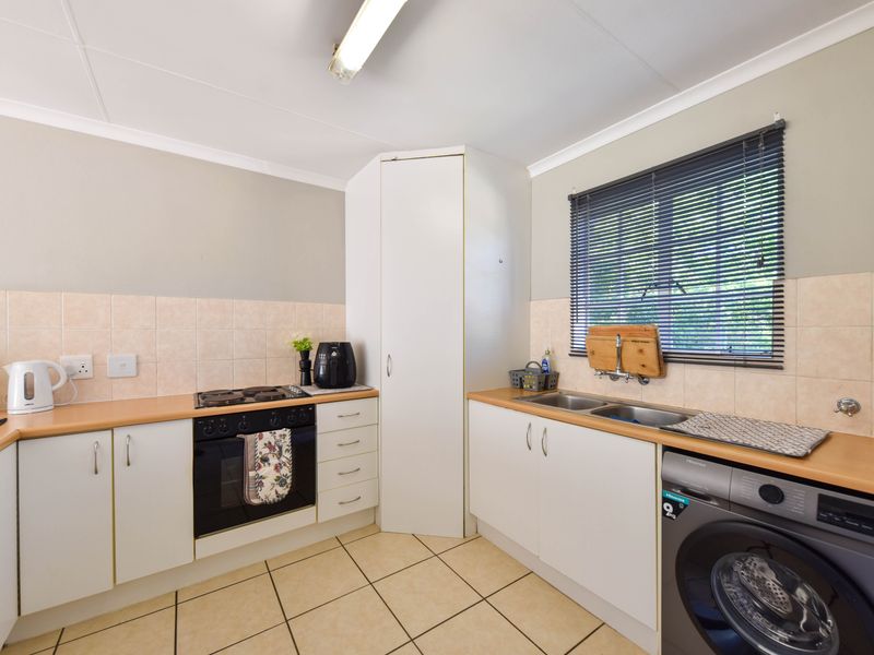 A functional kitchen featuring built-in cabinetry, laminate countertops, a double basin sink, and integrated oven and hob with tiled backsplash and flooring.