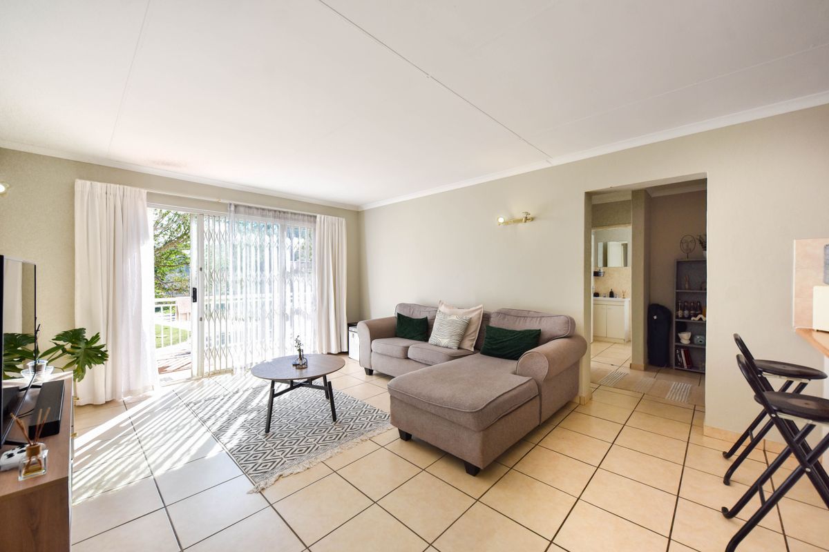 Spacious living area featuring neutral tiled flooring, coved ceilings, and a large sliding glass door providing access to the outdoor space.