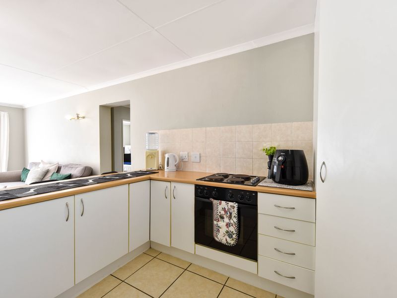 A functional kitchen featuring white cabinetry, laminate countertops, a tiled backsplash, and a built-in oven with an electric hob.