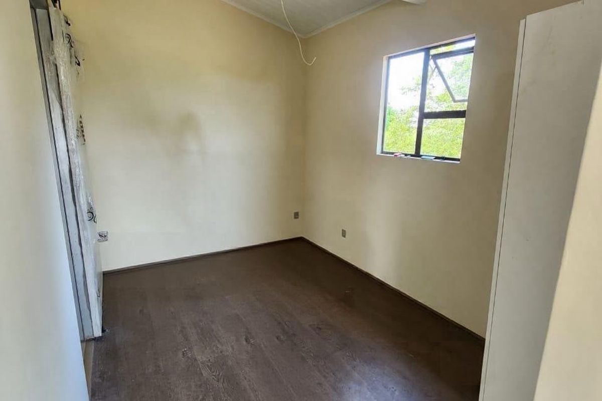 A vacant bedroom featuring vaulted timber ceilings, laminate flooring, and a sliding barn door, offering a blank canvas for personalization.