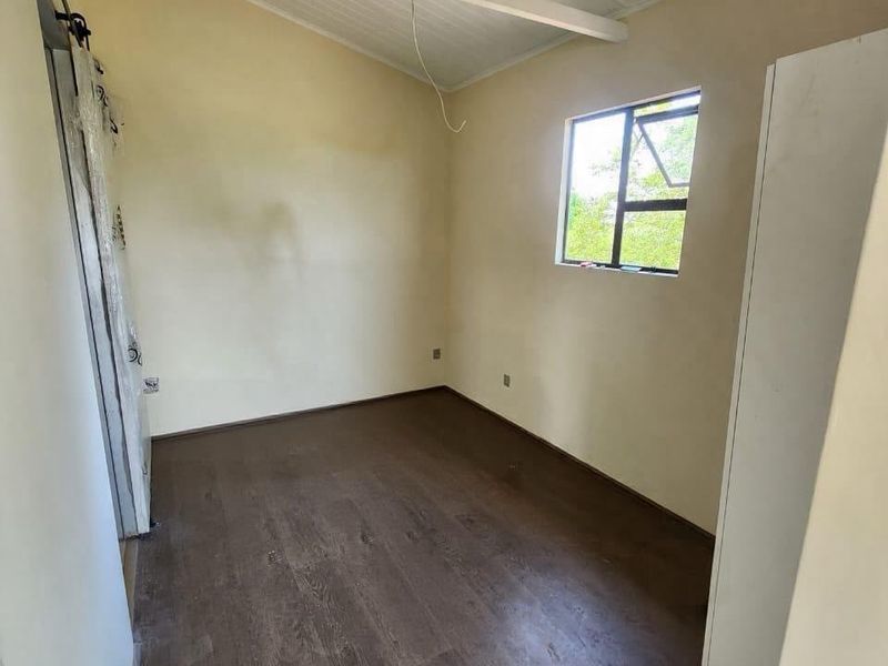 A vacant bedroom featuring vaulted timber ceilings, laminate flooring, and a sliding barn door, offering a blank canvas for personalization.