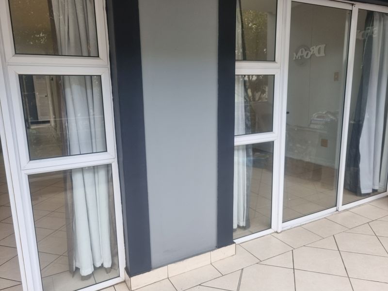 A clean, tiled balcony area featuring modern aluminium sliding glass doors providing access to the interior living space.