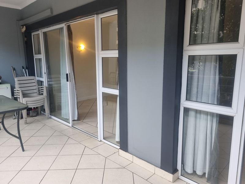A covered balcony area featuring tiled flooring and large sliding glass doors providing access to the interior living space.