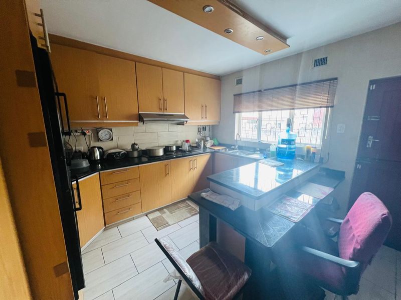 A functional kitchen featuring wood-finish cabinetry, granite countertops, a breakfast bar, and tiled flooring, providing a practical workspace with integrated storage and lighting.
