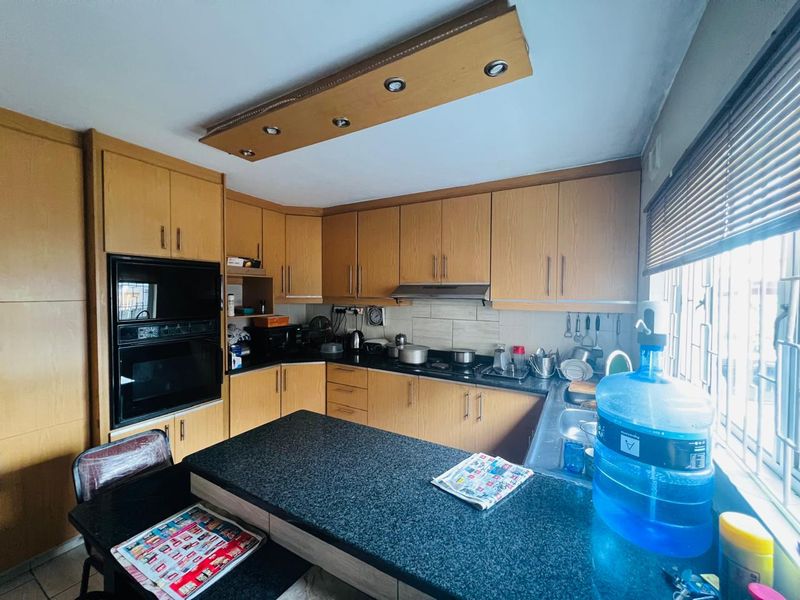 A functional kitchen featuring wood-finish cabinetry, granite countertops, a built-in oven, and an integrated extractor fan with ample workspace.