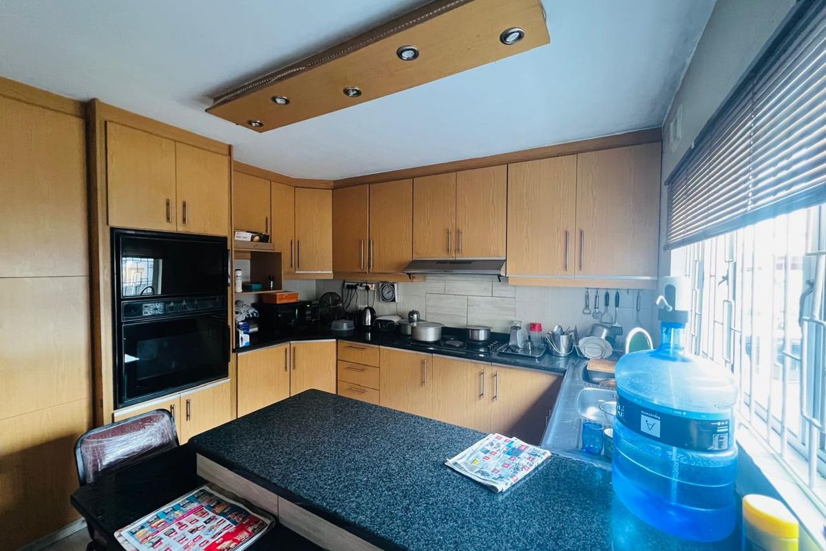 A functional kitchen featuring wood-finish cabinetry, granite countertops, a built-in oven, and an integrated extractor fan with ample workspace.