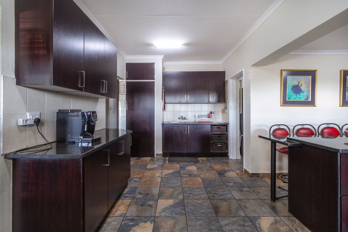 A functional kitchen featuring dark wood cabinetry, granite countertops, and durable tiled flooring, offering a practical layout with ample storage space.