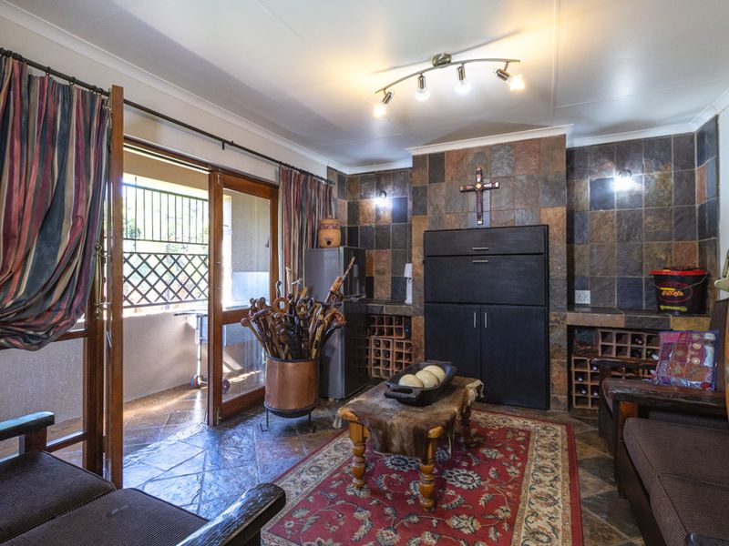 A rustic bar area featuring stone tile wall cladding, built-in wine storage, and direct access to an outdoor patio through sliding glass doors.