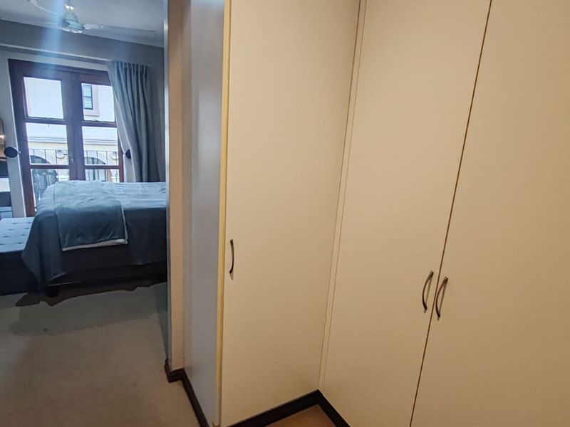 Bedroom featuring built-in cupboards and access to a balcony through double doors, providing natural light and ventilation.