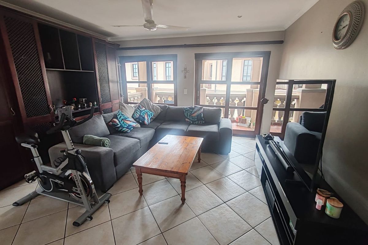 A comfortable living room featuring tiled flooring, built-in cabinetry, and sliding glass doors that provide access to an outdoor balcony area.