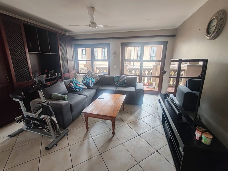 A comfortable living room featuring tiled flooring, built-in cabinetry, and sliding glass doors that provide access to an outdoor balcony area.