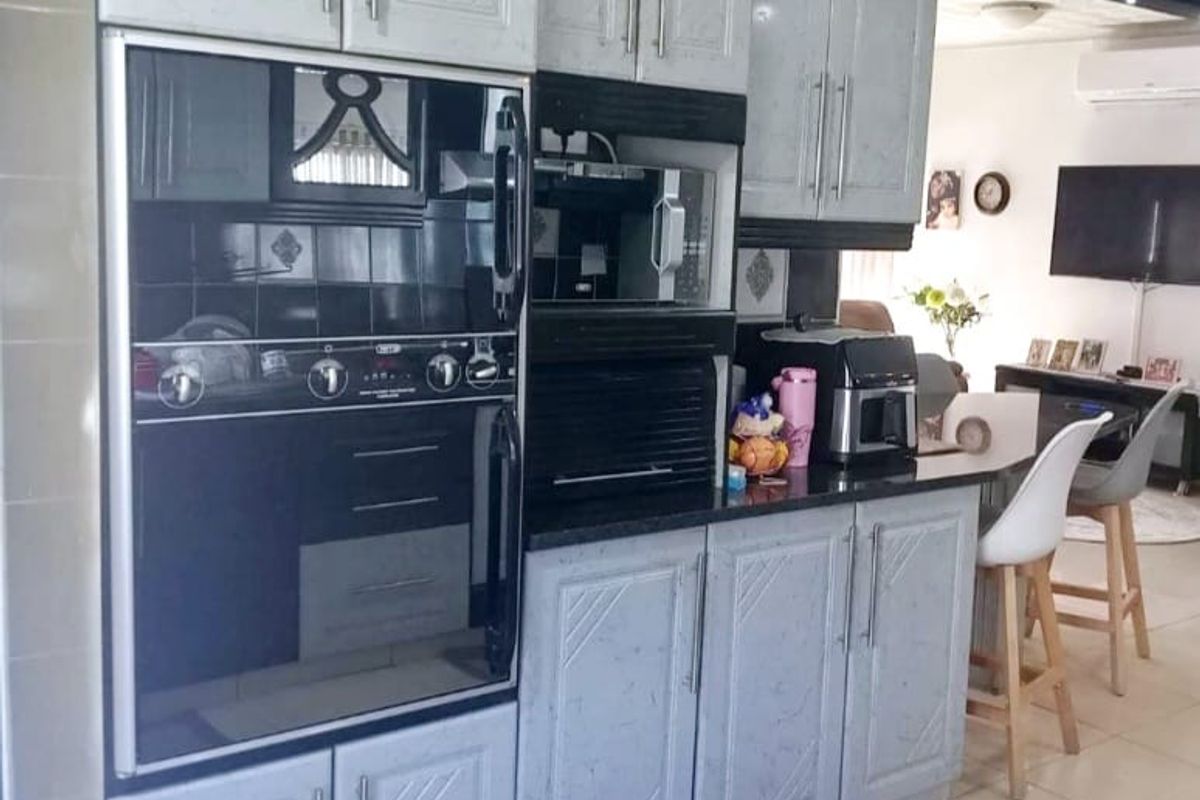 A functional kitchen featuring built-in oven and microwave units, ample cabinetry, and black granite countertops, seamlessly flowing into the adjacent living area.